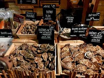 banc de marché qui présente des huîtres et des coquillages papytaine